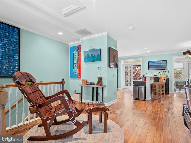 sitting room with plenty of natural light, light hardwood / wood-style floors, and ornamental molding