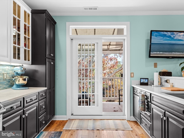 doorway to outside with light hardwood / wood-style floors and ornamental molding