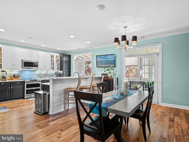 dining room with ornamental molding, a healthy amount of sunlight, and light wood-type flooring