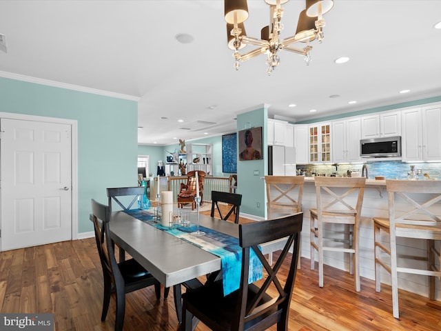 dining space featuring light wood-type flooring, an inviting chandelier, and crown molding