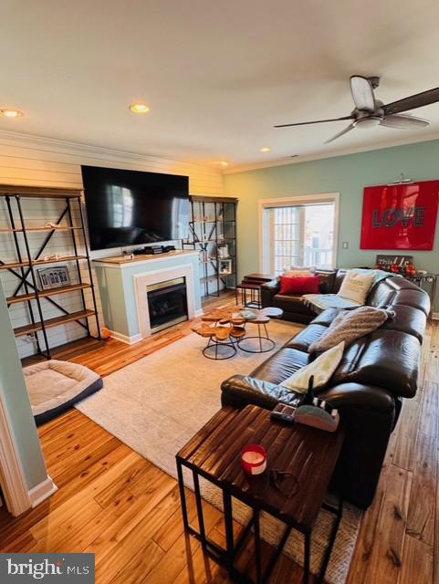 living room with ceiling fan, ornamental molding, and hardwood / wood-style flooring