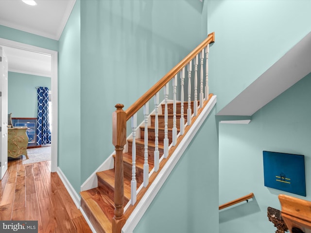 stairway featuring wood-type flooring and crown molding