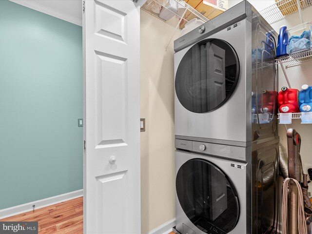 laundry area with stacked washer and dryer and hardwood / wood-style floors