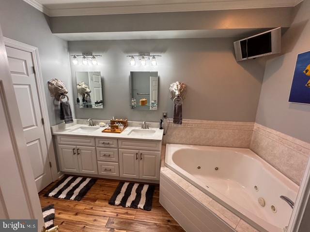 bathroom featuring tiled bath, crown molding, vanity, and hardwood / wood-style flooring