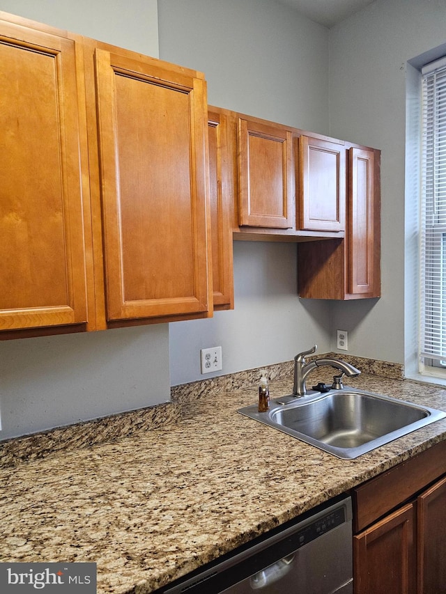 kitchen with light stone counters, stainless steel dishwasher, and sink