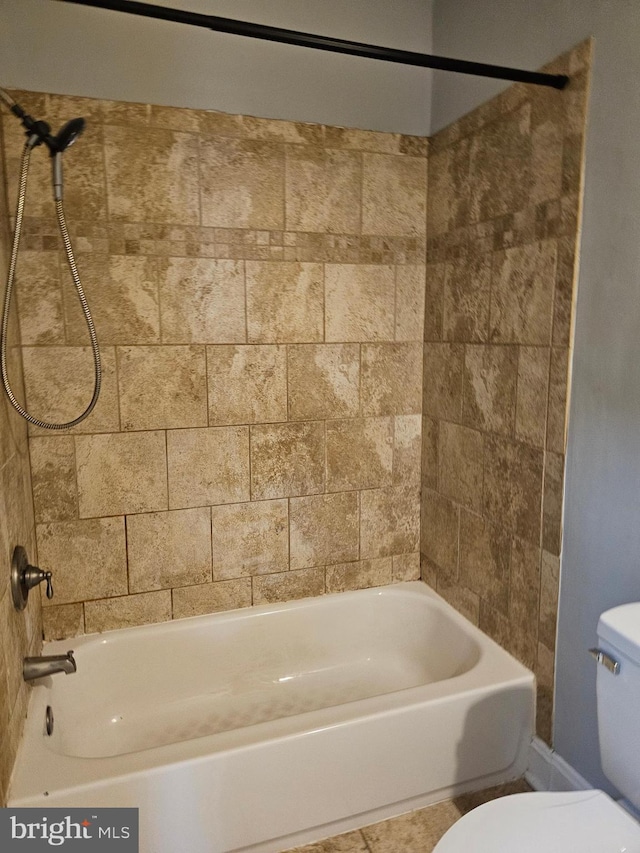 bathroom with toilet and tiled shower / bath