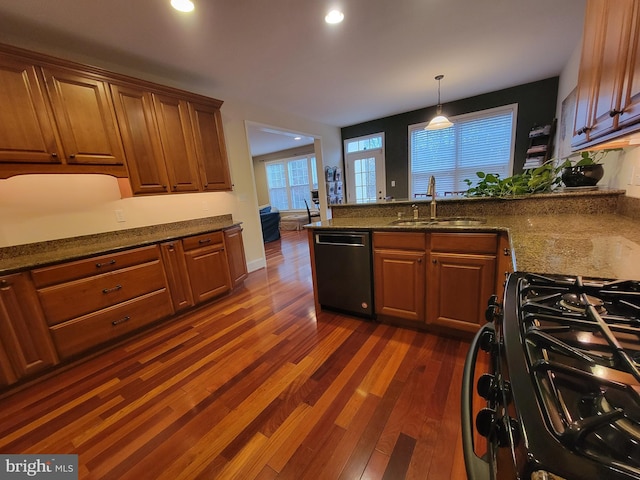 kitchen featuring stainless steel dishwasher, dark stone counters, gas range, dark wood-type flooring, and sink