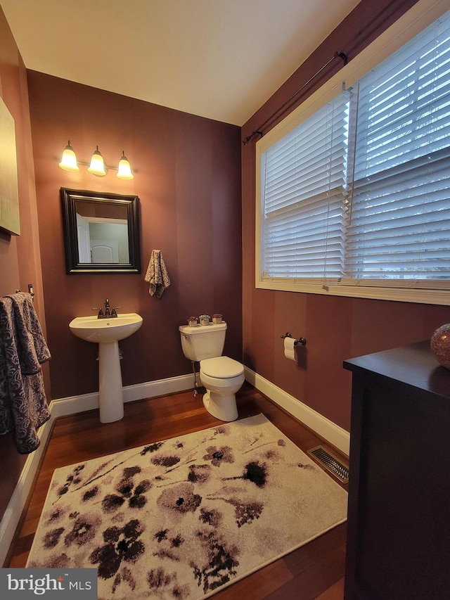 bathroom with hardwood / wood-style flooring, toilet, and a healthy amount of sunlight