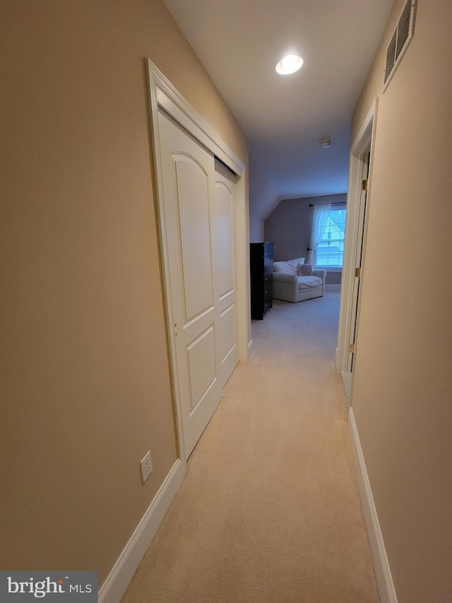 hall featuring light colored carpet and lofted ceiling