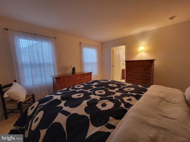 bedroom with ensuite bathroom and light carpet