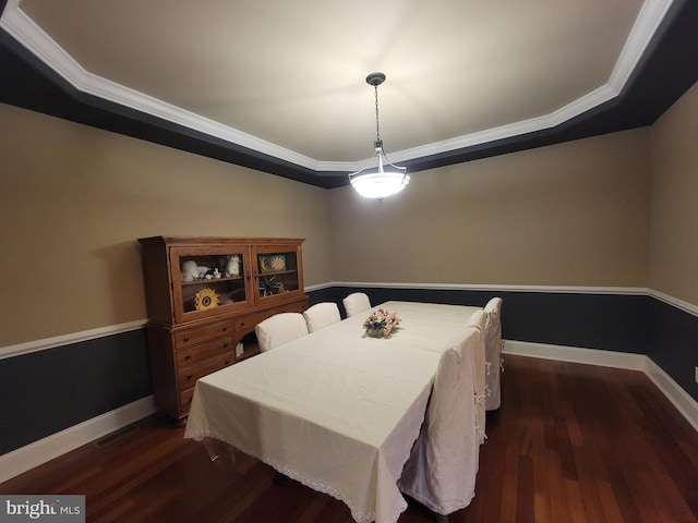 dining space featuring dark hardwood / wood-style floors, a raised ceiling, and ornamental molding