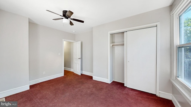 unfurnished bedroom featuring dark colored carpet, ceiling fan, and a closet