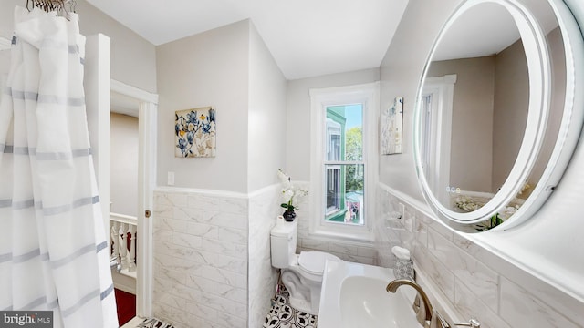 bathroom with tile walls, sink, and toilet