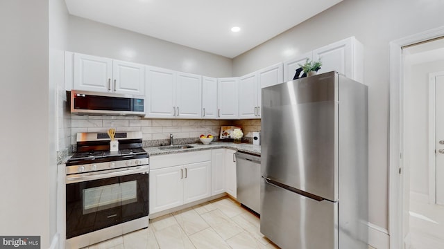 kitchen with white cabinetry, stainless steel appliances, sink, and backsplash