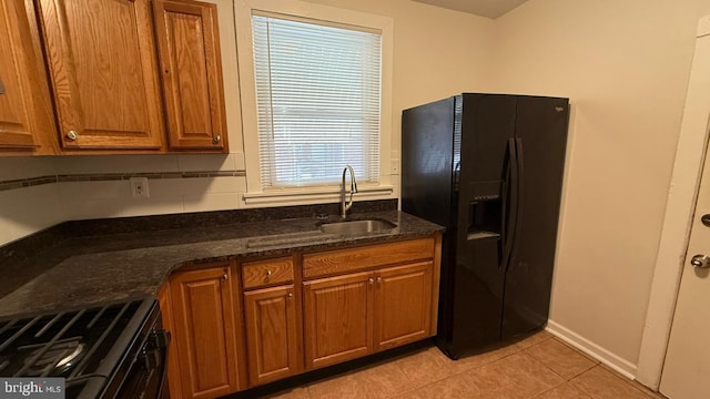 kitchen featuring black appliances, sink, tasteful backsplash, light tile patterned flooring, and dark stone countertops