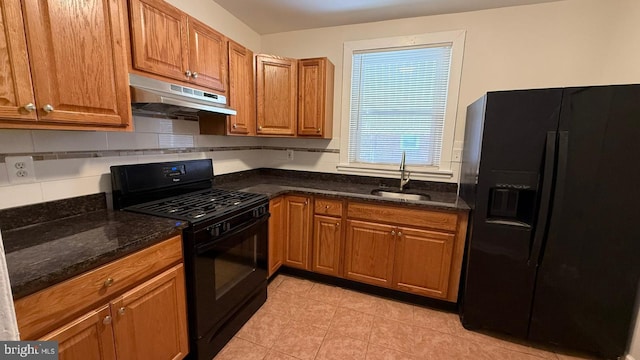 kitchen featuring black appliances, tasteful backsplash, light tile patterned floors, sink, and dark stone countertops