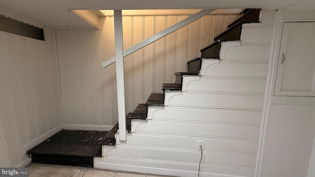 stairway featuring wood walls