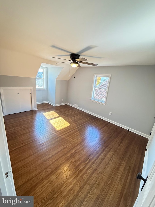 additional living space with vaulted ceiling, dark wood-type flooring, and plenty of natural light