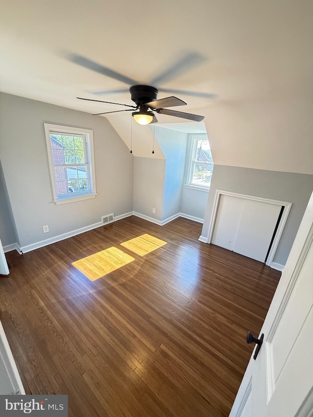 additional living space featuring ceiling fan, dark wood-type flooring, a healthy amount of sunlight, and lofted ceiling