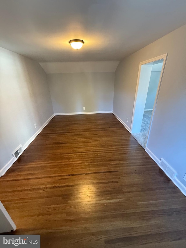 unfurnished room featuring lofted ceiling and dark wood-type flooring