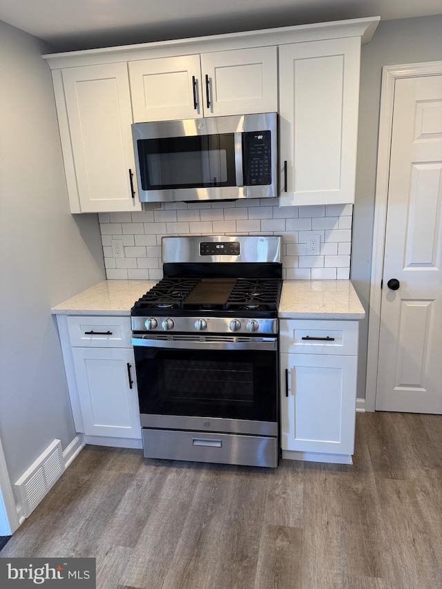 kitchen featuring white cabinets, hardwood / wood-style floors, stainless steel appliances, and tasteful backsplash