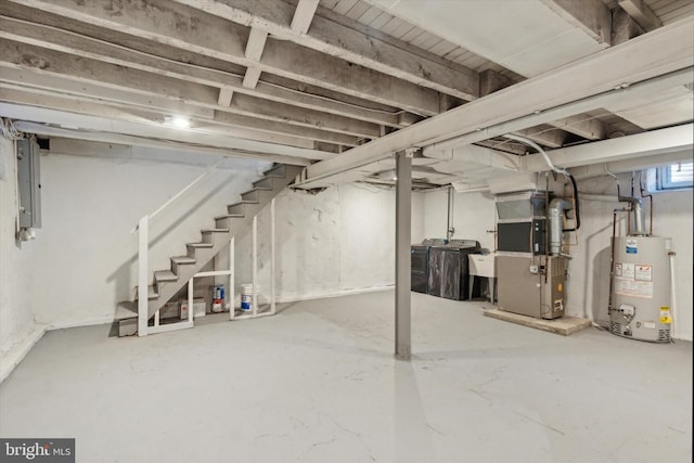 basement featuring washing machine and clothes dryer, heating unit, electric panel, and gas water heater