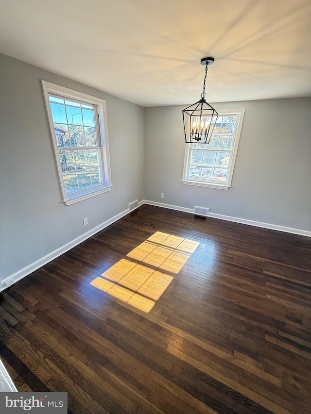 unfurnished dining area featuring dark hardwood / wood-style flooring and a notable chandelier