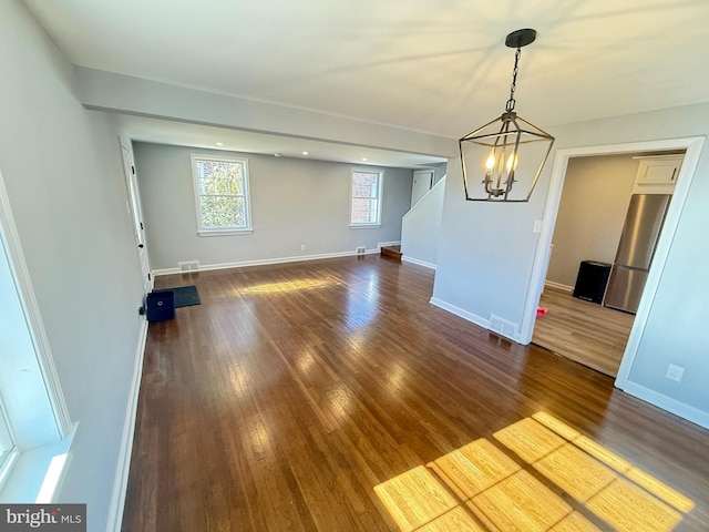 spare room with a chandelier and dark hardwood / wood-style flooring