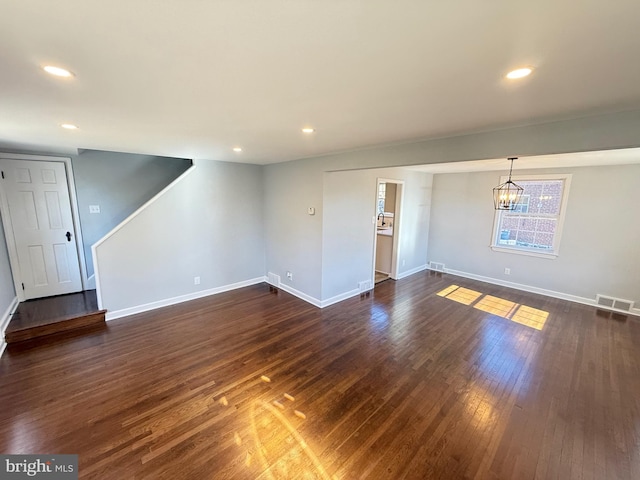 unfurnished living room featuring dark hardwood / wood-style flooring and an inviting chandelier