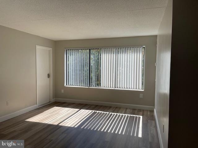 unfurnished room featuring dark hardwood / wood-style floors and a textured ceiling