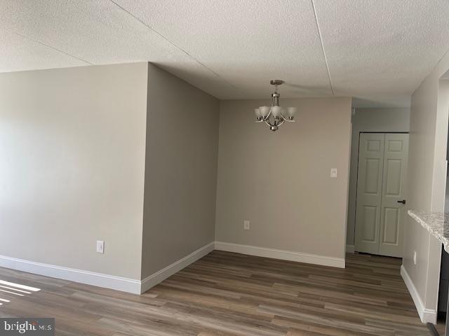 unfurnished room featuring an inviting chandelier, dark hardwood / wood-style floors, and a textured ceiling