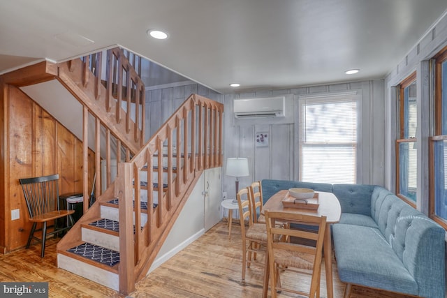 dining room featuring a wall mounted air conditioner and light hardwood / wood-style flooring