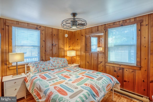 bedroom with multiple windows, wooden walls, and light wood-type flooring