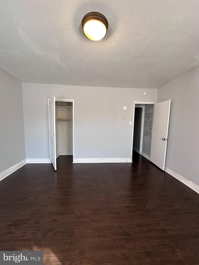 unfurnished room featuring dark wood-type flooring and a textured ceiling