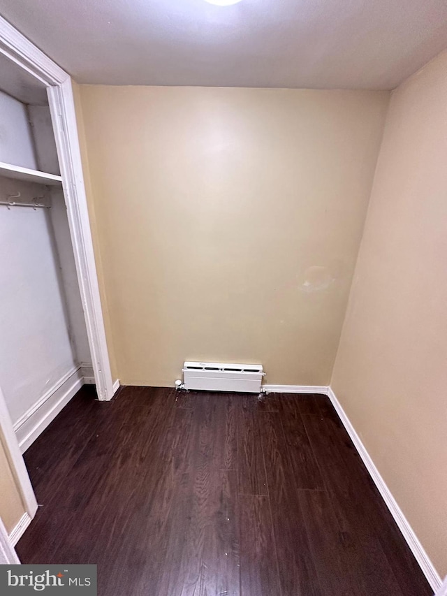 unfurnished bedroom with a closet, a baseboard radiator, and dark hardwood / wood-style flooring