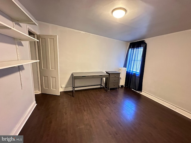 empty room with dark wood-type flooring and radiator