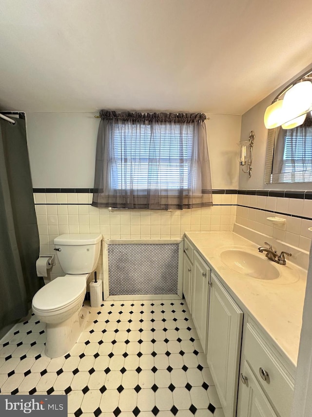 bathroom featuring tile walls, radiator heating unit, vanity, and toilet