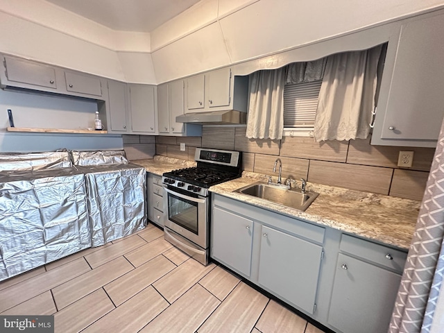 kitchen with gas range, sink, tasteful backsplash, and gray cabinetry