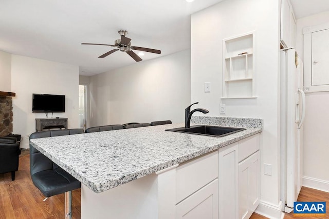 kitchen featuring sink, white cabinets, kitchen peninsula, a breakfast bar area, and light hardwood / wood-style flooring