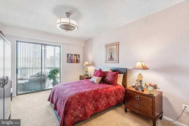 bedroom with access to exterior, light colored carpet, and a textured ceiling