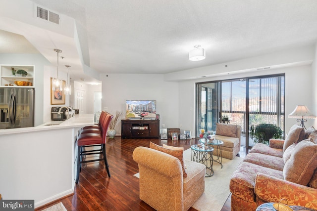 living room featuring a textured ceiling, dark hardwood / wood-style flooring, and sink