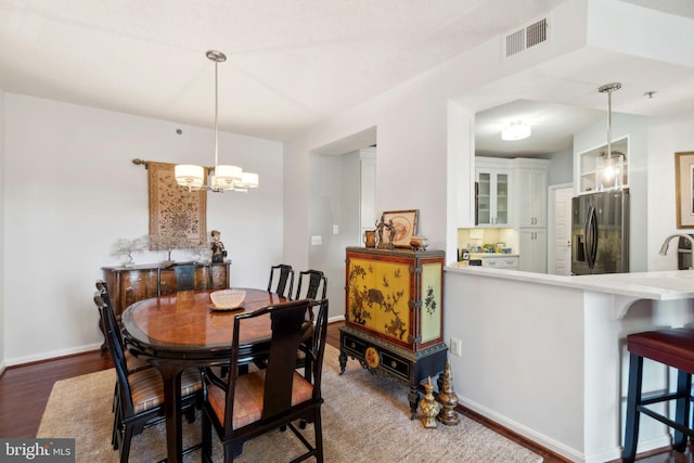 dining room featuring a chandelier, sink, and wood-type flooring