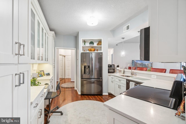 kitchen featuring stainless steel fridge, dark hardwood / wood-style flooring, a textured ceiling, white cabinetry, and hanging light fixtures