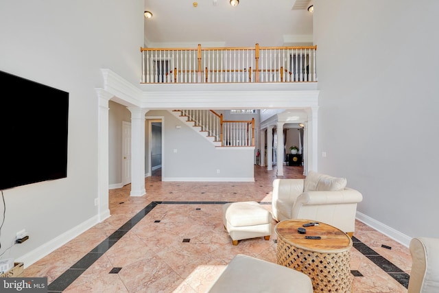 living room featuring decorative columns and a towering ceiling