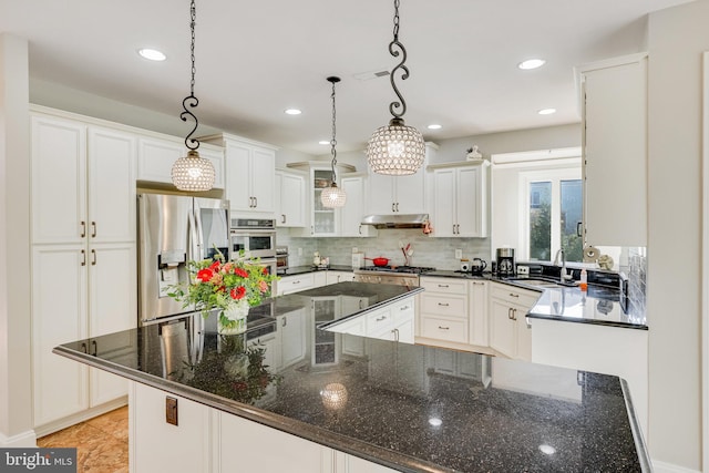 kitchen featuring stainless steel appliances, sink, decorative light fixtures, dark stone countertops, and white cabinets