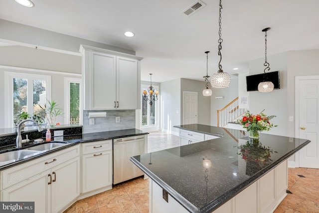 kitchen featuring stainless steel dishwasher, dark stone counters, a spacious island, sink, and white cabinetry