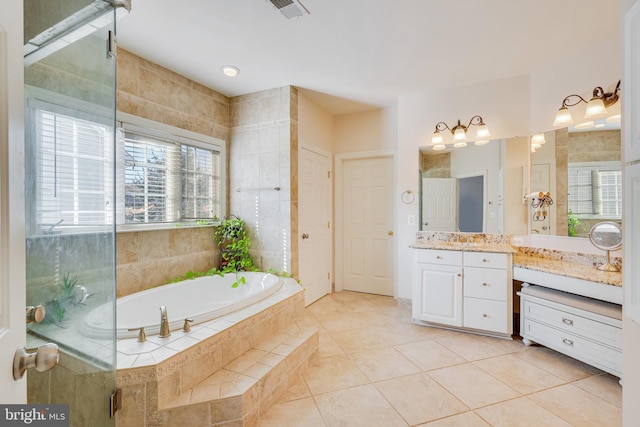 bathroom with tiled bath, tile patterned flooring, vanity, and tile walls