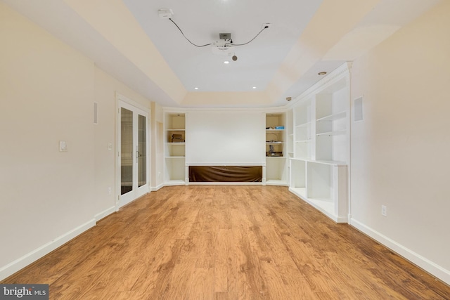 empty room with hardwood / wood-style floors, a raised ceiling, and french doors