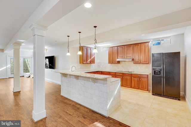 kitchen featuring black fridge, kitchen peninsula, hanging light fixtures, and light hardwood / wood-style flooring