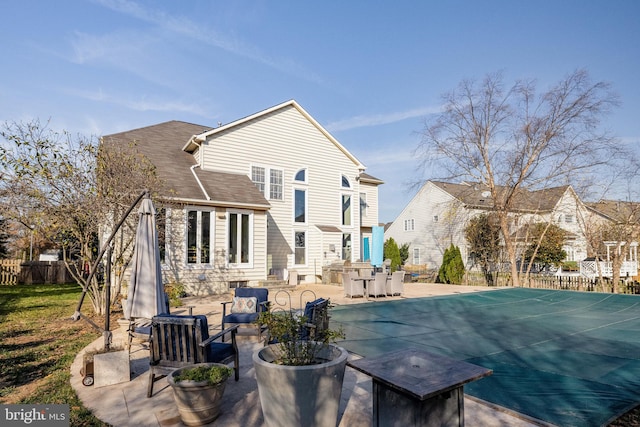 rear view of house with a patio area and a covered pool